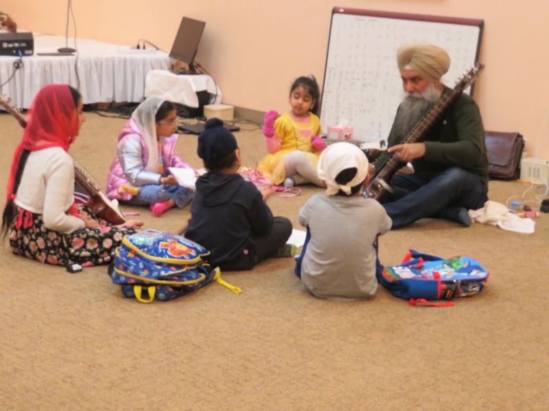 Young children learning stringed instruments in a circle