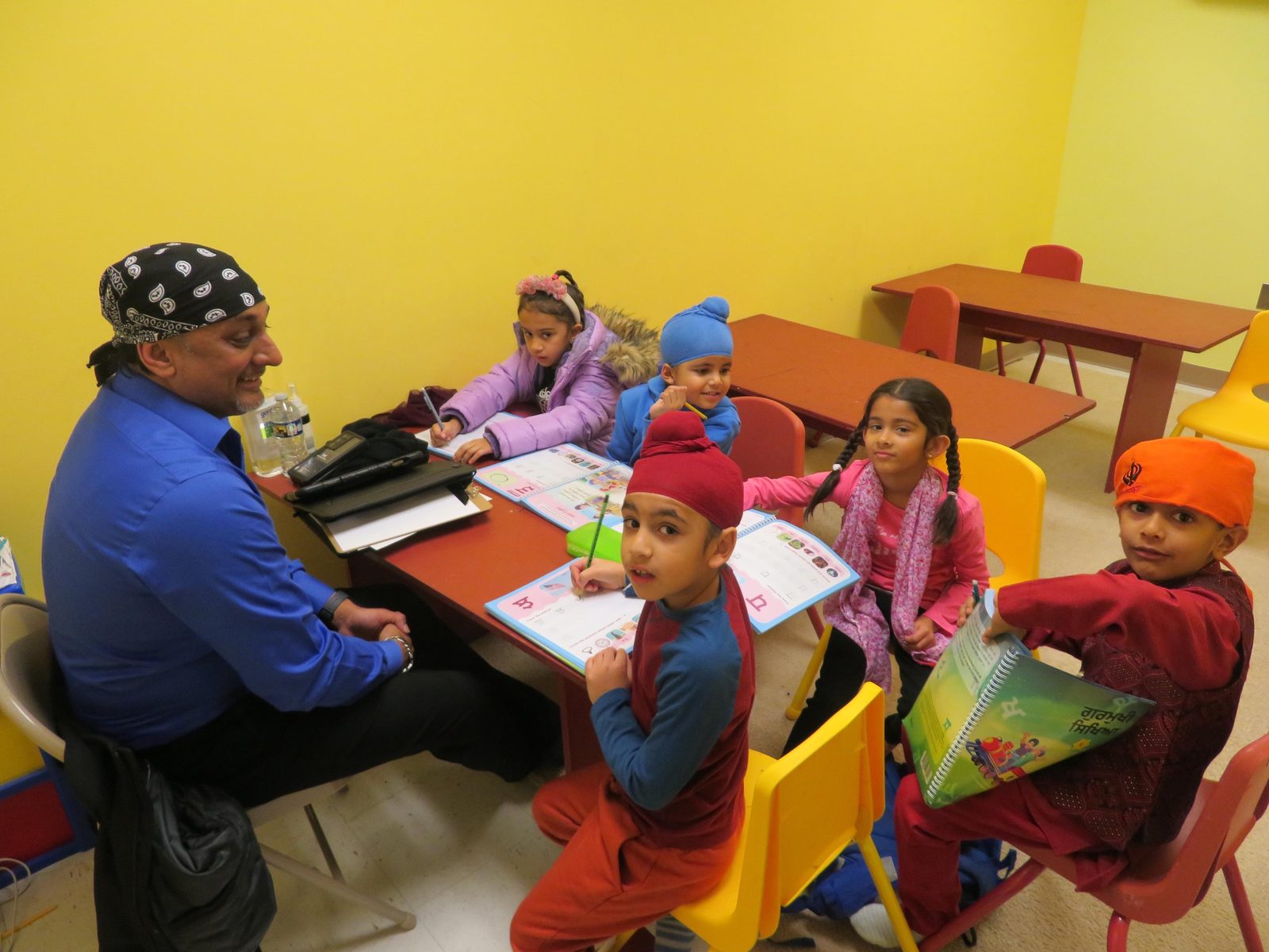 A GAISS teacher working closely with young students at a table